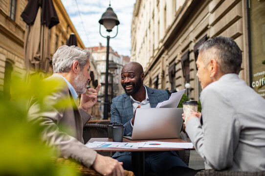 Business colleagues meeting with laptop at outdoor cafe in city