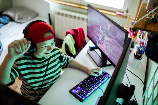 Happy teenage gamer playing pc in bedroom at home