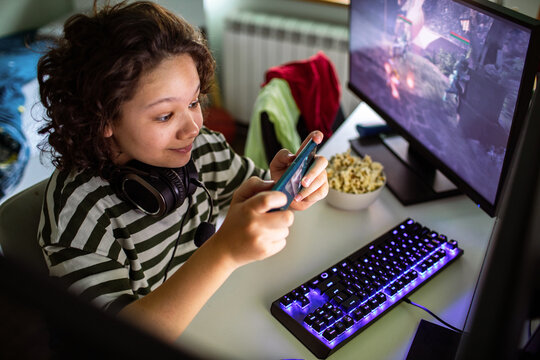 Teen gamer playing mobile game at home desk