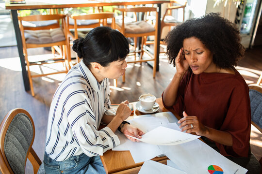 Two women reviewing financial documents at a cafe