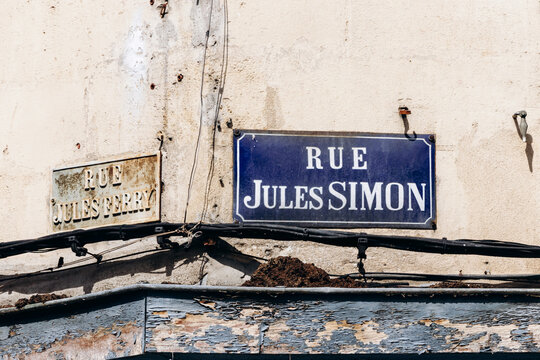 Weathered street name plaques for Rue Jules Simon and Rue Jules Ferry mounted on an old wall in Libourne, Nouvelle-Aquitaine, France