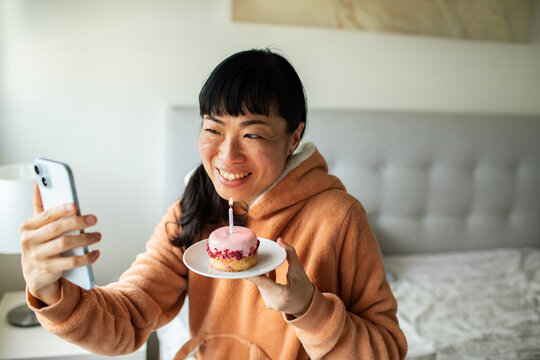 Smiling woman video calling with birthday cupcake at home