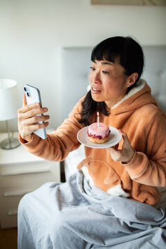Woman on video call with birthday cupcake at home