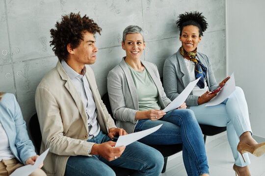 Group of young businss people sitting in chairs and waiting for an interview holding application documents