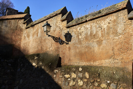 View of a historic brick wall with a vintage lantern in Andalusia, Spain.