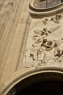 View of intricate stone relief carvings of angels and figures on a historic church facade under bright sunlight in Andalusia, Spain.