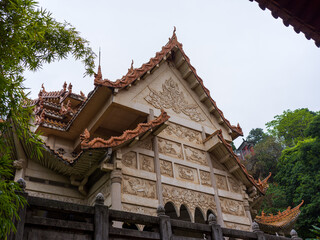 Obraz premium Low angle view of white stone carved temple facade with greenery