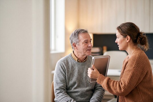 Senior man consulting with a female specialist holding a mirror in a modern clinic