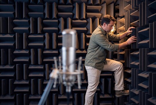 Acoustic Engineer Inspecting Soundproofing Foam Panels Inside an Anechoic Testing Chamber with Studio Microphone
