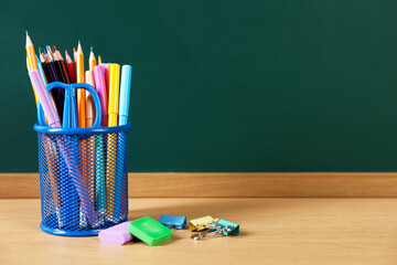 Different stationery on wooden table near chalkboard. Space for text © New Africa