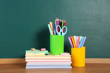 Books, notebooks and stationery on wooden table against chalkboard © New Africa