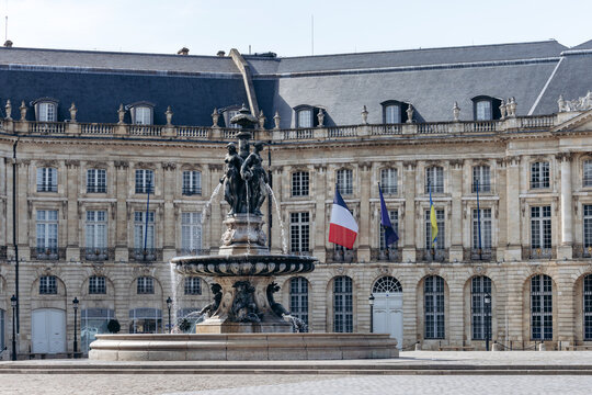Bordeaux, France - July 14, 2026: Monumental fountain on Place de la Bourse with historic neoclassical architecture and French flag
