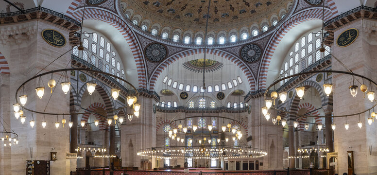 View of the ornate interior of the Suleymaniye Mosque with its grand dome, intricate calligraphy, and large circular chandeliers hanging above the prayer hall in Istanbul, Istanbul, Turkiye.