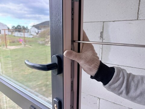 Window frame adjustment. Worker use a screwdriver to adjust the new windows. Manual window frame adjustment