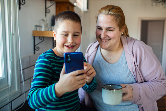 Mother and son looking at smartphone in kitchen