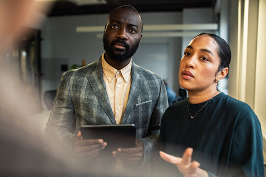 Two coworkers discussing strategy with tablet in office
