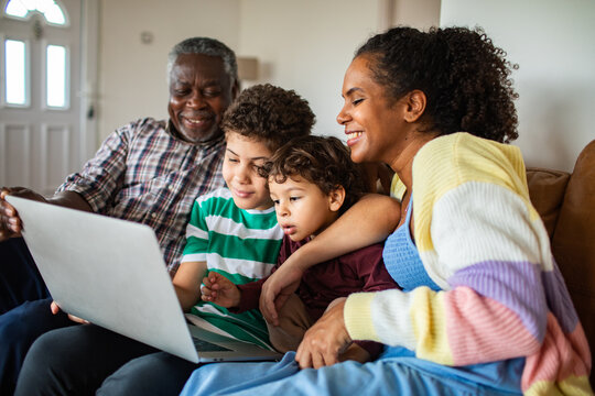 Grandfather, mother and kids watching laptop on couch at home