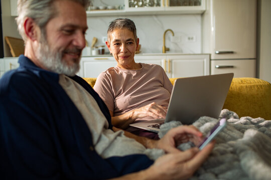 Senior couple using laptop and smartphone at home