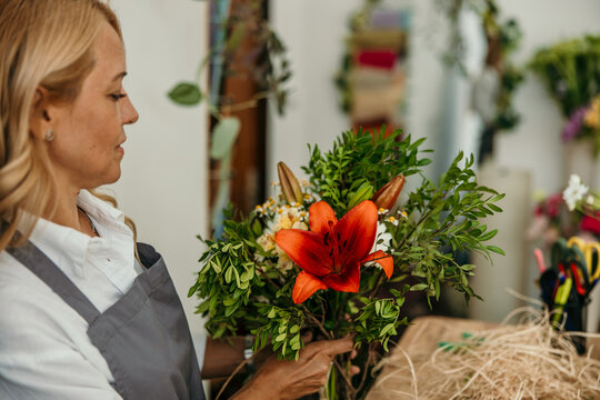 Florist woman arranging beautiful flower bouquet in shop
