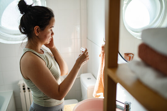 Concerned woman reading pregnancy test result in home bathroom