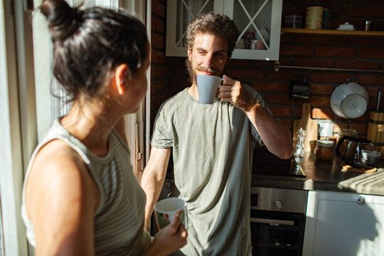 Young couple sharing morning coffee in sunlit home kitchen