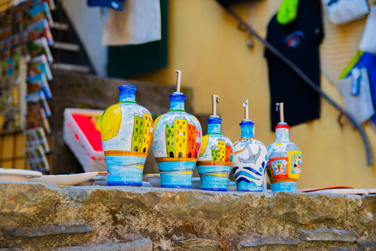 Colorful hand-painted ceramic bottles displayed on a stone ledge in Cinque Terre, Italy, featuring traditional Mediterranean designs, coastal colors and local artisan craftsmanship.