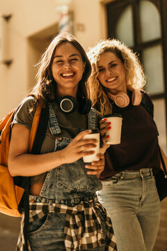 Happy young women friends enjoying coffee outdoors