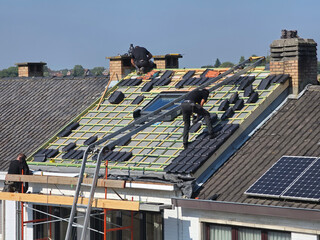 Ouvriers qui rénovent la toiture d’une maison pour isolation et remplacement des tuiles © joef