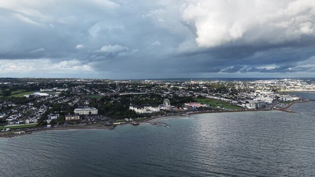 Wide cinematic aerial drone footage overlooking Salthill and Galway, Ireland, from across Galway Bay. The scene features the Salthill Promenade, coastal shoreline, residential neighborhoods, green