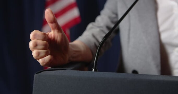 Speaker clenches fist at podium with American flag