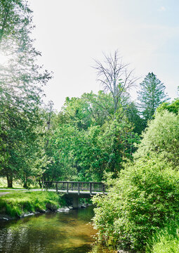 scenic view of Geyser Creek flowing underneath a wooden pedestrian bridge inside Saratoga Spa State Park, Saratoga Springs, New York