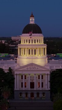 The California State Capitol in Sacramento under evening skies with the dome brightly lit and surrounded by trees.