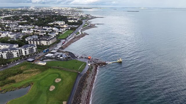 Panoramic drone footage flying along the famous Salthill coastline in Galway, Ireland. The video captures the iconic Blackrock Diving Tower, Salthill Promenade, Galway Bay, the nearby golf course
