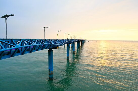 Cox's Bazar District, Chittagong Division, Bangladesh - 14 September 2026: View of the long blue metal pier at Teknaf Beach stretching into the calm sea during a golden sunset.