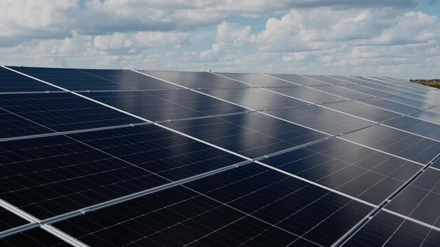 Rows of solar panels reflect clouds and blue sky, creating an attractive image of modern clean energy.