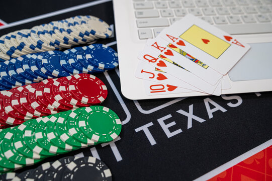 Top View of Royal Flush Hearts Hand with Casino Tokens and Laptop for Virtual Poker Game