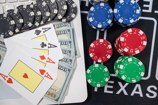Four Aces Playing Cards with US Dollar Bills Laptop Keyboard and Chips for Online Poker Game