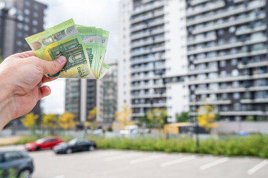 Close up of Hand Holding Euro Currency Bills in Front of New Residential Complex Exterior