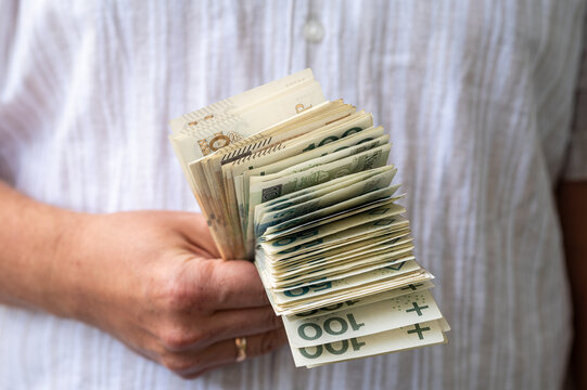 Close up of Male Hands Holding Big Stack of Polish Money Bills for Salary Payment Concept