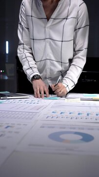Business professional analyzing corporate financial data using digital tablet and documents, managing workload in late office hours, planning investment strategy and market growth