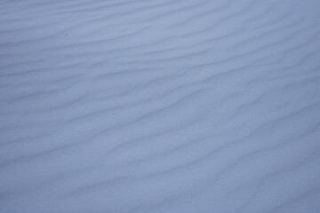 Obraz premium Fine-grained rippled sand surface is stretching diagonally in close-up dune scene, bluish tint