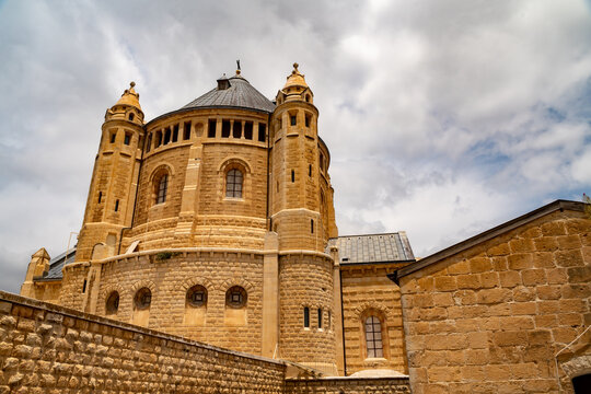 Jerusalem, Israel - 19 May 2023: View of the historic Dormition Abbey with its distinctive stone architecture and towers under a cloudy sky.