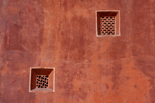Terracotta wall with traditional carved jali windows in Hawa Mahal. Red sandstone texture background of Hawa Mahal palace wall in Jaipur, India, with small square decorative lattice windows