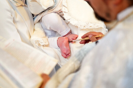 A priest anoints a newborn baby's feet with chrism during the baptism and anointing ceremony.