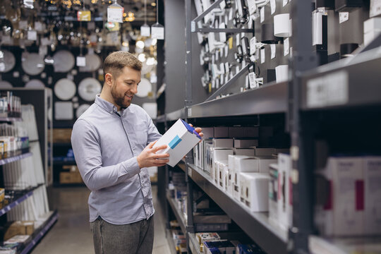 Man shopping for lighting fixtures in a retail store, choosing new lights, consumerism and retail experience