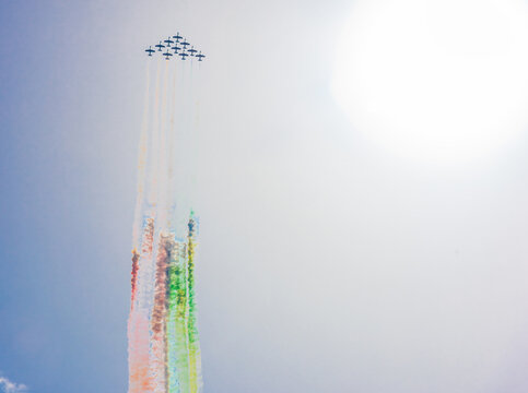 Frecce Tricolori flying upward in formation with colorful smoke trails