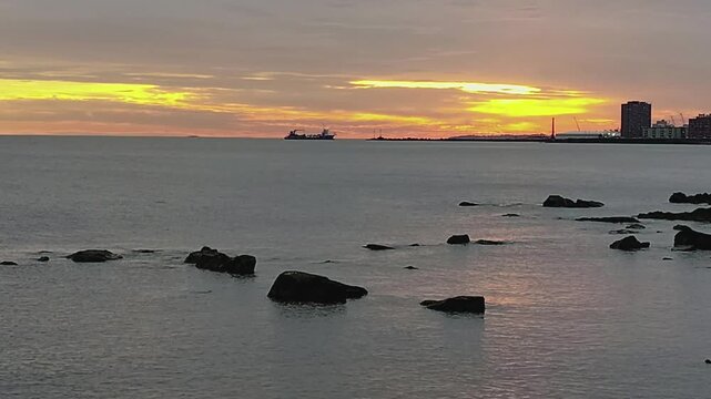 Small ship crossing the river plate river during sunset afternoon in the city of Montevideo.