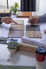Architect and Interior Designer Collaborating on Floor Plans with Wood Samples. © Supitnan