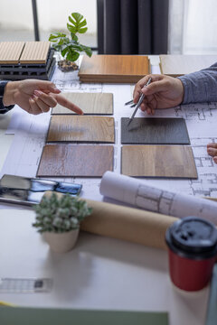 Architect and Interior Designer Collaborating on Floor Plans with Wood Samples.
