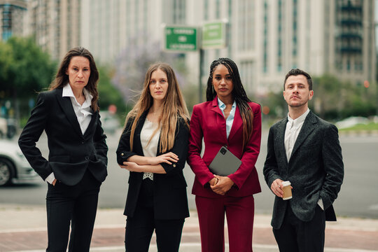 Diverse business professionals standing with confident expressions in city, representing leadership and success